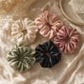Five Lullacurl silk satin scrunchies in cream, blush, sage, dusty rose, charcoal